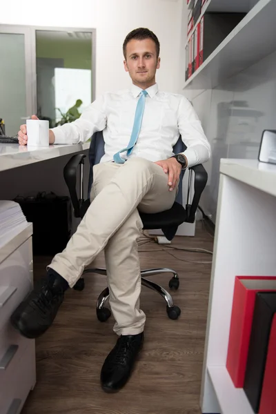 Jovem empresário relaxa sentado no escritório — Fotografia de Stock