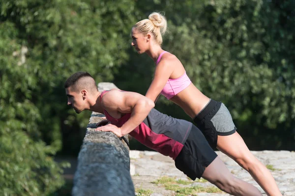 Joven pareja haciendo flexiones al aire libre — Foto de Stock