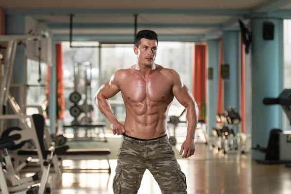 Hombre en el gimnasio mostrando su cuerpo bien entrenado —  Fotos de Stock