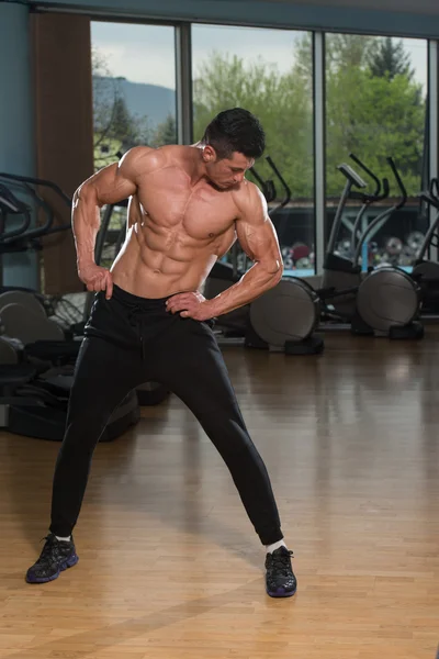 Ung Man Stretching innan träningen i gymmet — Stockfoto