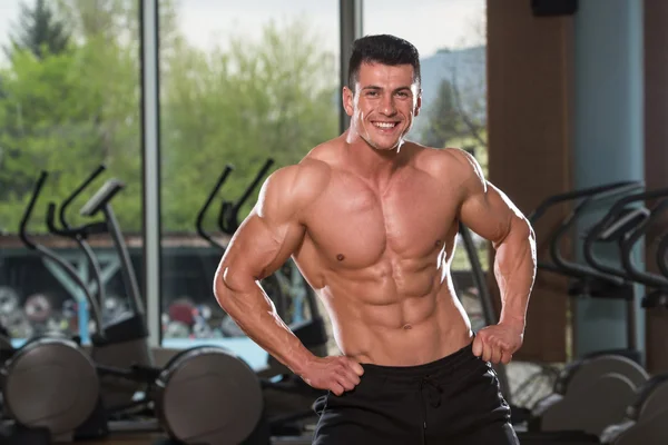 Hombre joven estirándose antes de hacer ejercicio en el gimnasio —  Fotos de Stock