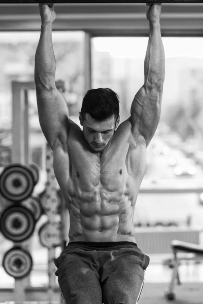 Jovem realizando pendurado perna levanta abdominais exercício — Fotografia de Stock