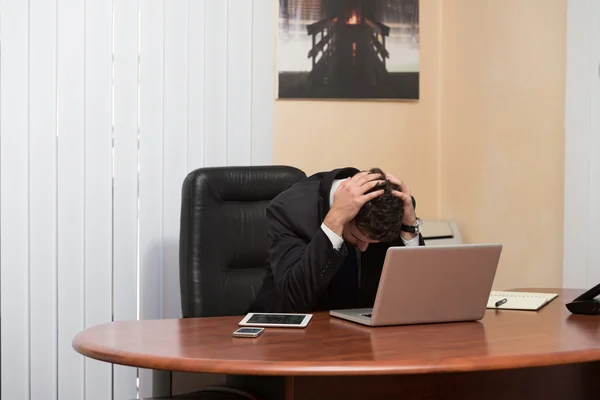 Молодой бизнесмен с проблемами в офисе — стоковое фото