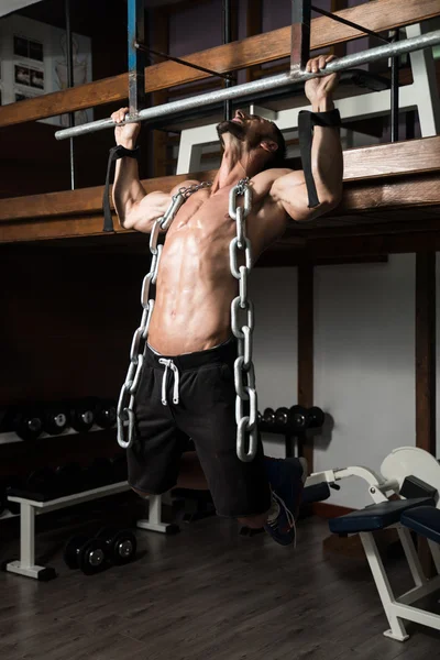 Człowiek robi ćwiczenia z powrotem z łańcuchów — Zdjęcie stockowe