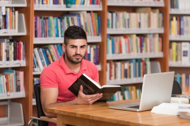 Diz üstü bir kütüphaneyi kullanan genç öğrenci