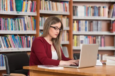 Diz üstü bir kütüphaneyi kullanan genç öğrenci