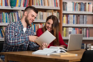 Mutlu öğrenciler dizüstü bilgisayar kitaplığı ile çalışma