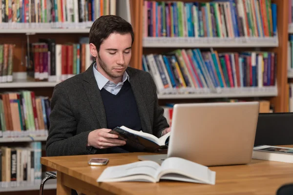 Ung Student med sin Laptop i ett bibliotek — Stockfoto