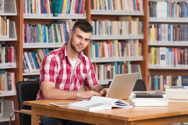 Felice studente maschio con computer portatile in biblioteca — Foto Stock