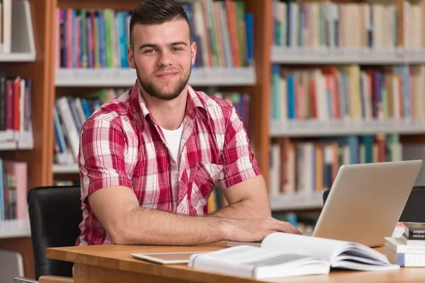 Mladý Student pomocí jeho notebook v knihovně — Stock fotografie