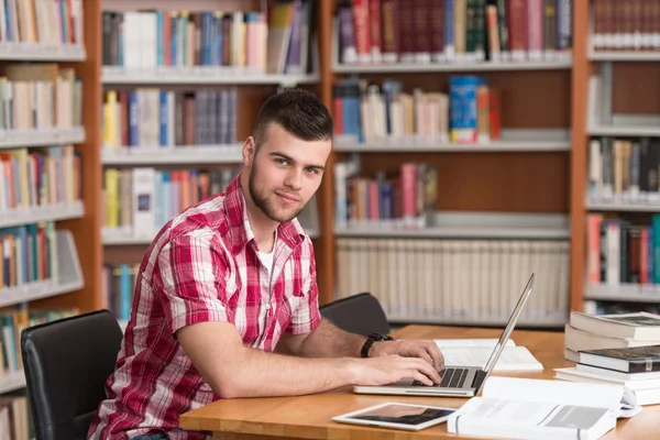 Ung Student med sin Laptop i ett bibliotek — Stockfoto