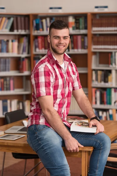 Красивый молодой студент колледжа в библиотеке — стоковое фото