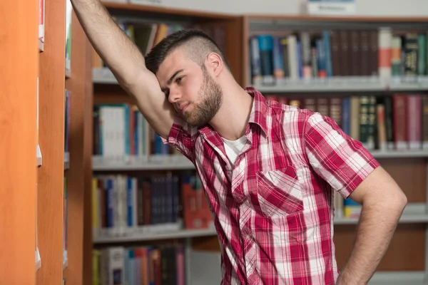 Запутавшийся студент-мужчина читает много книг для экзамена — стоковое фото