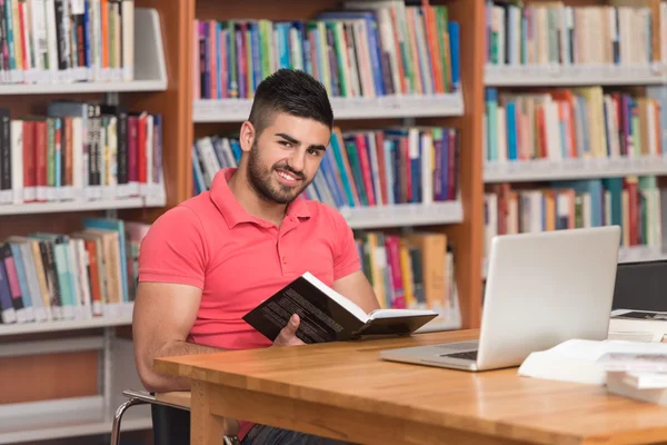 Estudiante masculino feliz trabajando con el ordenador portátil en la biblioteca — Foto de Stock
