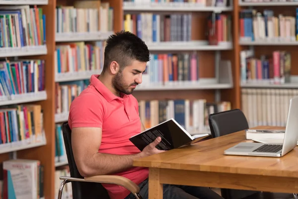 Jovem estudante usando seu laptop em uma biblioteca — Fotografia de Stock