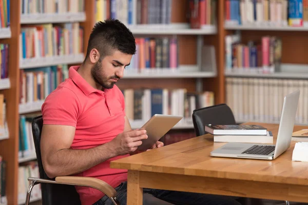 Mutlu erkek öğrenci dizüstü bilgisayar kitaplığı ile çalışma — Stok fotoğraf