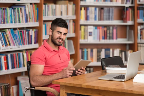 Estudiante joven usando su computadora portátil en una biblioteca — Foto de Stock