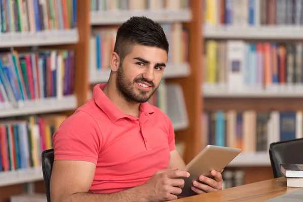 Estudiante masculino feliz trabajando con el ordenador portátil en la biblioteca — Foto de Stock