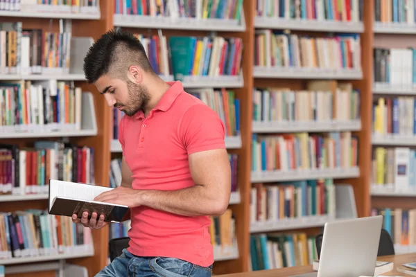 Feliz estudiante masculino con libro en la biblioteca — Foto de Stock