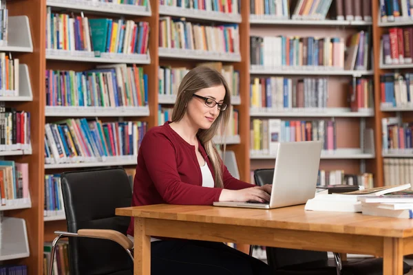 Ung Student med sin Laptop i ett bibliotek — Stockfoto