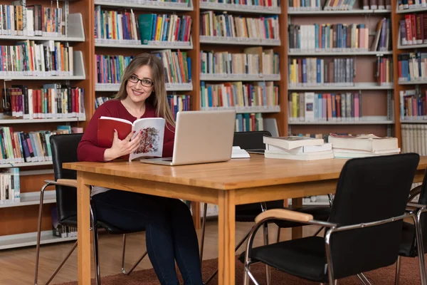 Estudante feminina feliz com laptop na biblioteca — Fotografia de Stock