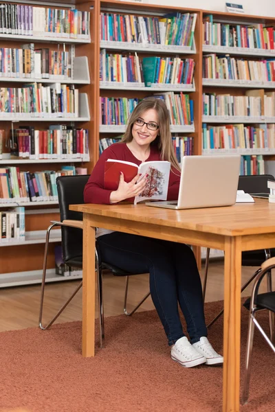 Jovem estudante usando seu laptop em uma biblioteca — Fotografia de Stock