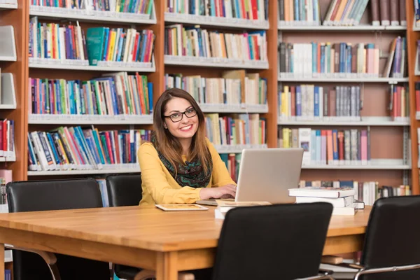 Ung Student med sin Laptop i ett bibliotek — Stockfoto