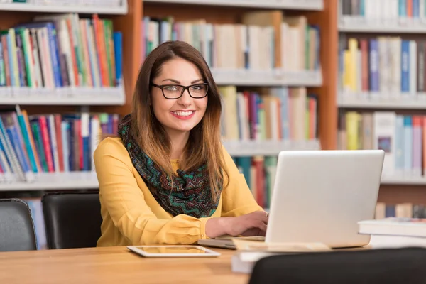 Mutlu kız öğrenci dizüstü bilgisayar kitaplığı ile çalışma — Stok fotoğraf