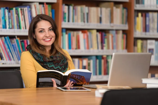 Estudante feminina feliz com laptop na biblioteca — Fotografia de Stock