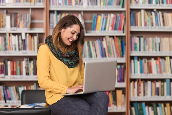 Glückliche Studentin arbeitet mit Laptop in Bibliothek — Stockfoto