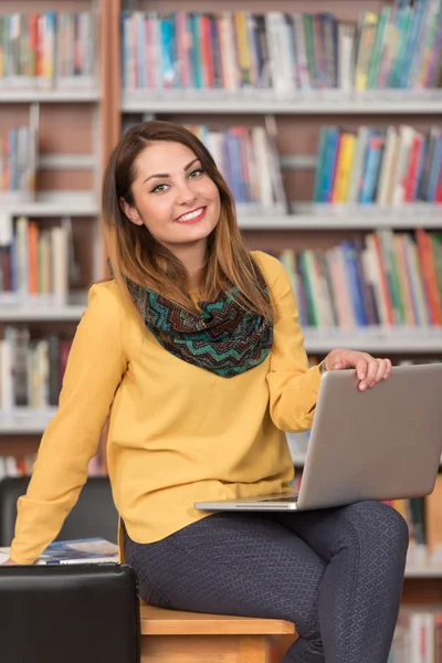 Молодой студент пользуется ноутбуком в библиотеке — стоковое фото