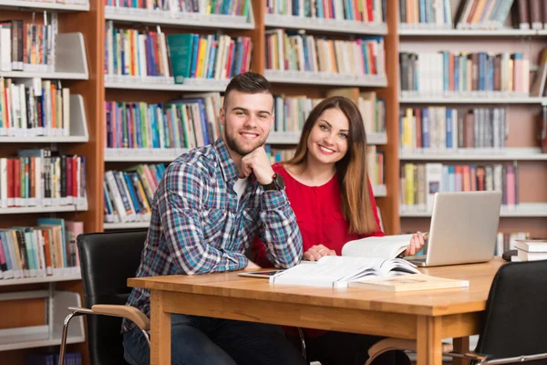 Onların Laptop bir kitaplığı kullanan genç öğrenciler — Stok fotoğraf