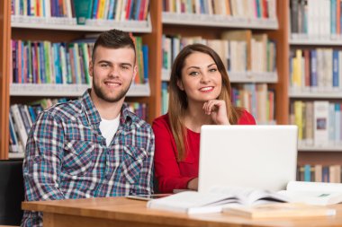 Bir kitaplıkta bir Tablet bilgisayar kullanan öğrenciler