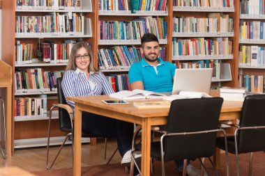 Mutlu öğrenciler dizüstü bilgisayar kitaplığı ile çalışma