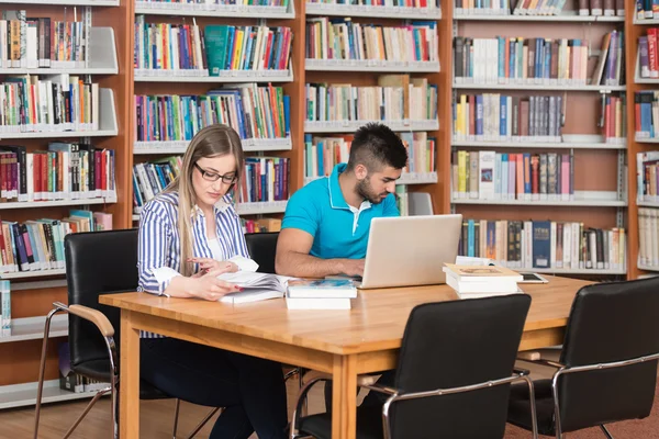 Heureux étudiants travaillant avec ordinateur portable dans la bibliothèque — Photo