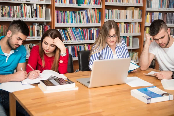 Skupina studentů s notebookem v knihovně — Stock fotografie