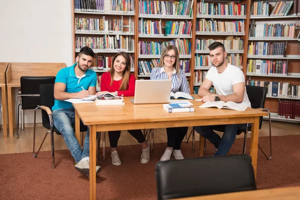 Heureux étudiants travaillant avec ordinateur portable dans la bibliothèque — Photo