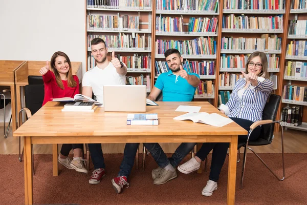 Öğrenciler başparmak göstermek yukarıya bir Kitaplığı'nda — Stok fotoğraf