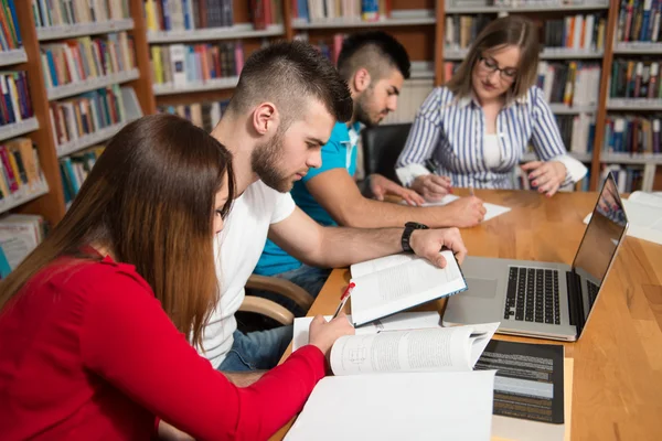 Skupina studentů s notebookem v knihovně — Stock fotografie