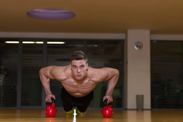 Ung Man utövar Push Ups på Kettle Bell — Stockfoto