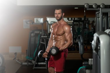 Kaslı adam pazılar için ağır ağırlık egzersizi yapıyor.