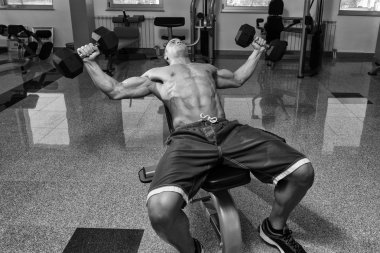 Genç adam dışarı göğüs dumbell ile çalışma