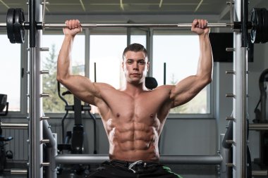 Omuzlar için ağır egzersiz yaparak erkek vücut geliştirmeci