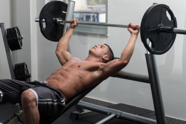 Kaslı adam göğüs için Bench Press egzersiz yaparak