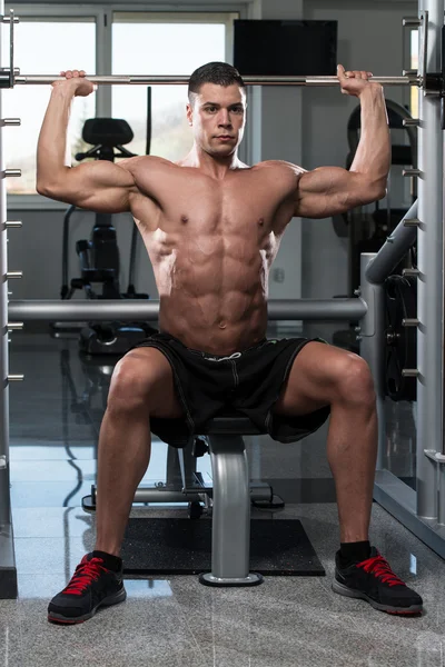 Bodybuilder trainiert Schultern mit Langhantel — Stockfoto