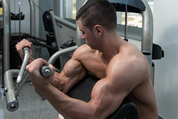 Człowiek w siłowni wykonywania Biceps na maszynie — Zdjęcie stockowe