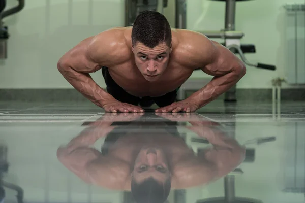 Jonge man doen pers ups in gym — Stockfoto