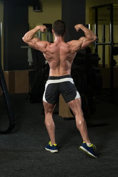 Bodybuilder presterende achterste dubbele biceps vormen — Stockfoto