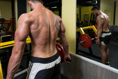 Genç adam spor salonunda sırt egzersizleri yapıyor
