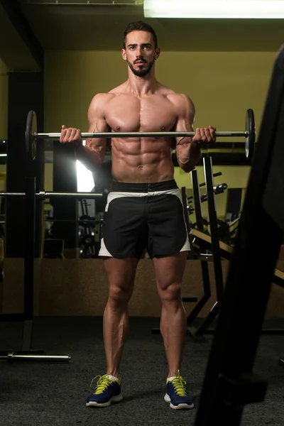 Hombre en el gimnasio ejercitando bíceps con barra —  Fotos de Stock